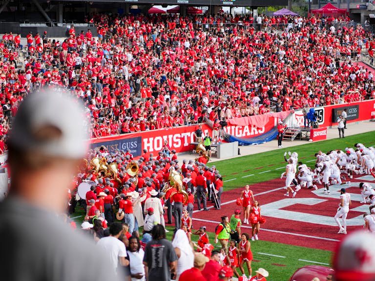 Cheerful fans at a college football game in Houston, TX, showcasing school spirit and vibrant energy.